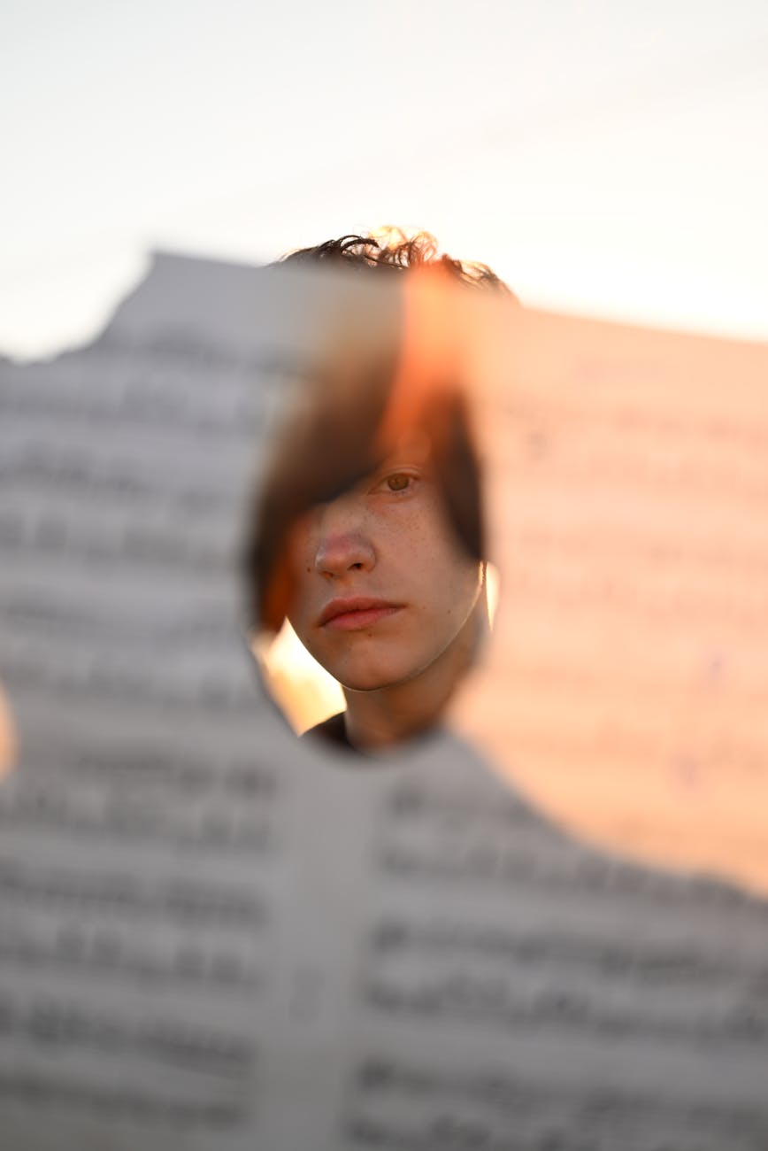 portrait of man seen through hole burned in book page